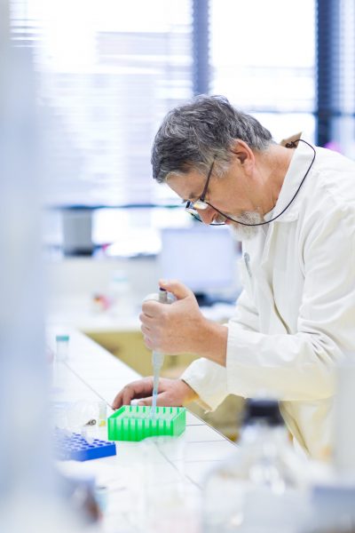 senior male researcher carrying out scientific research in a lab (shallow DOF; color toned image)